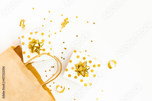 Obraz na płótnie Top view of golden dotted gift boxes, a shopping bag and star shaped golden confetti on a white background. Copy space. w salonie