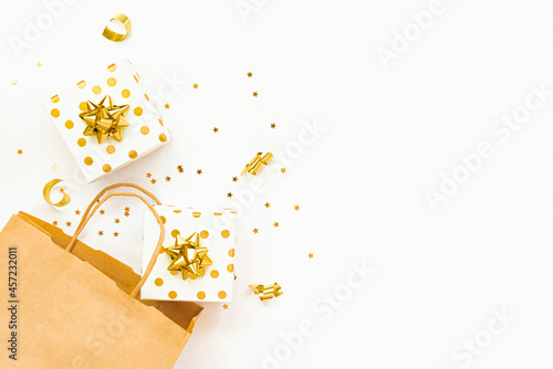 Obraz na płótnie Top view of golden dotted gift boxes, a shopping bag and star shaped golden confetti on a white background. Copy space. w salonie