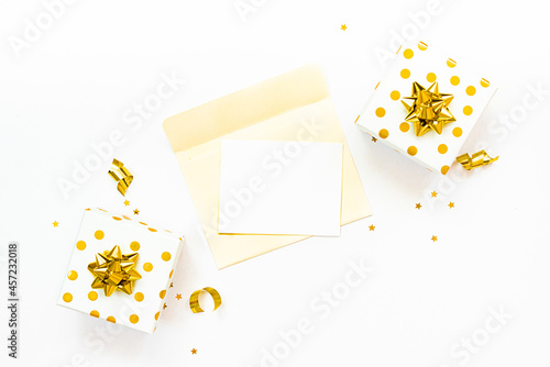 Obraz na płótnie Top view of golden dotted gift boxes and open envelope with empty card on a white background. Copy space, mock-up. w salonie