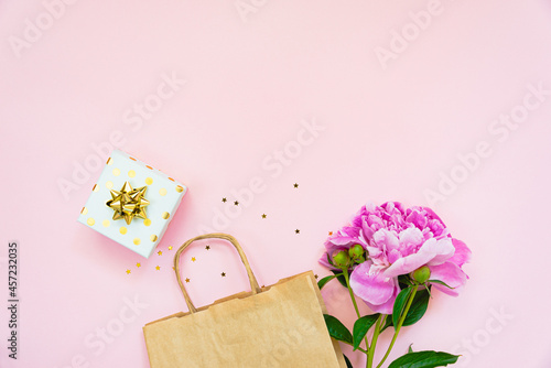 Obraz na płótnie Flat lay of a gift box, a shopping bag and a peony flower over pink background. Copy space. w salonie