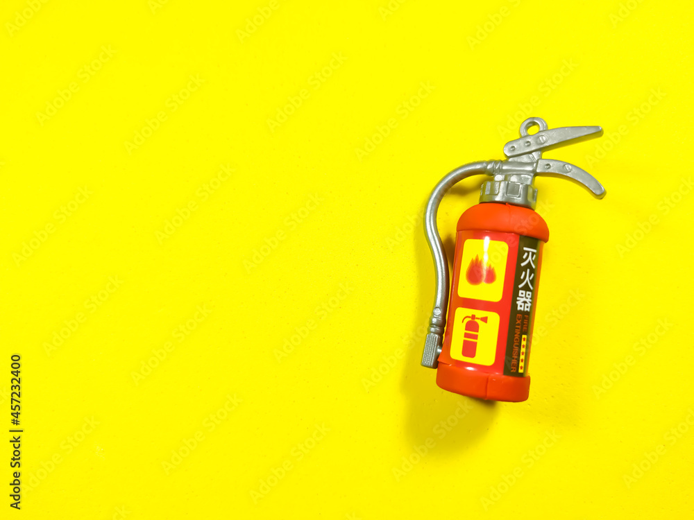 Toy fire extinguisher on a yellow background with copy space. Toy fire extinguisher on a yellow background with copy space.