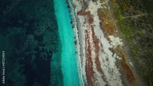 Cinemagraph seamless video loop at the seaside on the island Sardinia in Italy. Aerial of a natural white sand beach tourist vacation sea coast bay with clear blue water and yellow and green bushes.
