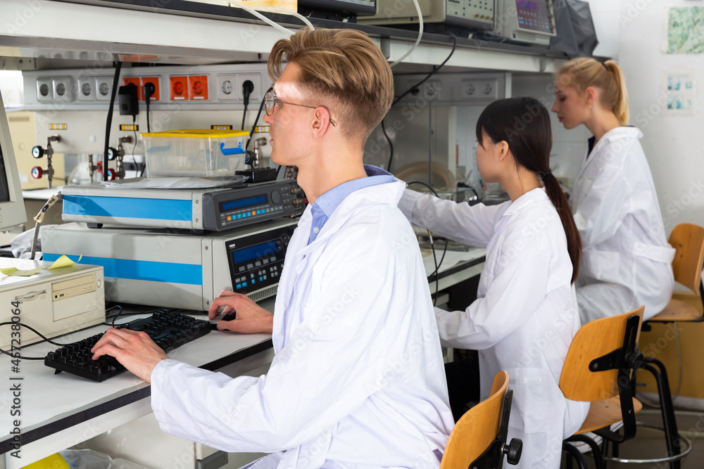 Obraz premium Portrait of young male scientist engaged in research in chemical laboratory with his female colleagues