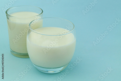 Two glasses of milk or cream on blue background 