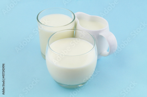 Jug with milk and two glasses of milk on blue background. 