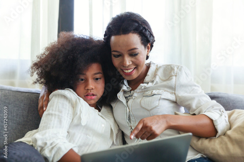 Mother And Daughter spending time together on sofa and using Digital Tablet at home