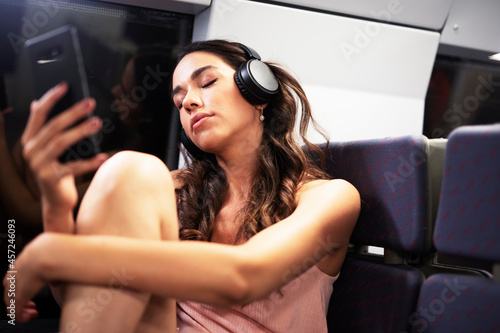Young woman travelling by train. Beautiful girl listening the music while travel..