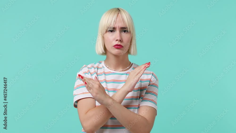 Serious strict severe young blonde short haircut woman 20s wears striped t-shirt say no hold palm folded crossed hands in stop gesture isolated on pastel plain light blue background studio portrait Serious strict severe young blonde short haircut woman 20s wears striped t-shirt say no hold palm folded crossed hands in stop gesture isolated on pastel plain light blue background studio portrait
