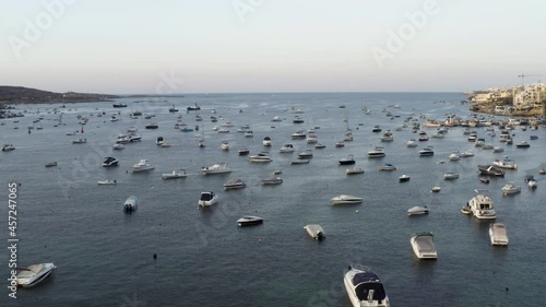 Aerial shot flying over hundreds of anchored yachts in a sea bay,Malta.