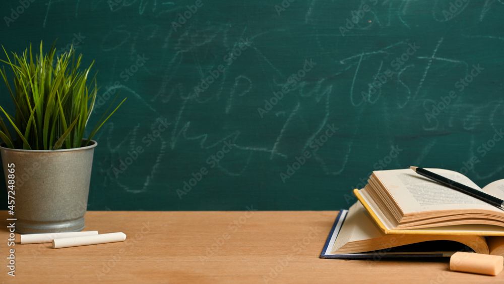 Mockup space on wooden table with opened books, pencil over green blackboard. Classroom Mockup space on wooden table with opened books, pencil over green blackboard. Classroom