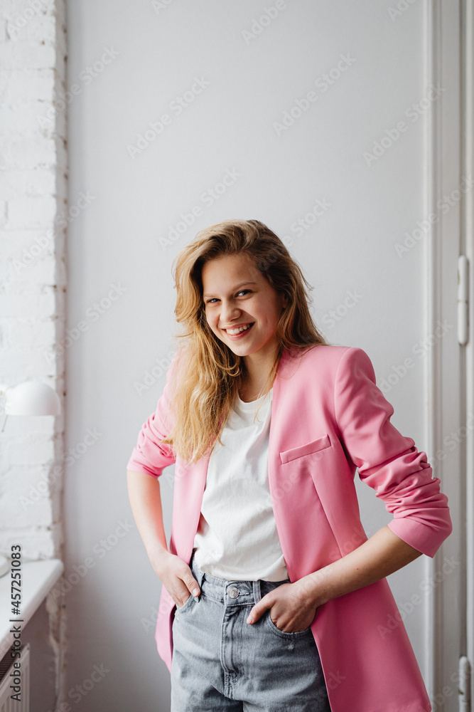 Beautiful teenage girl with long blonde hair wearing a pink jacket