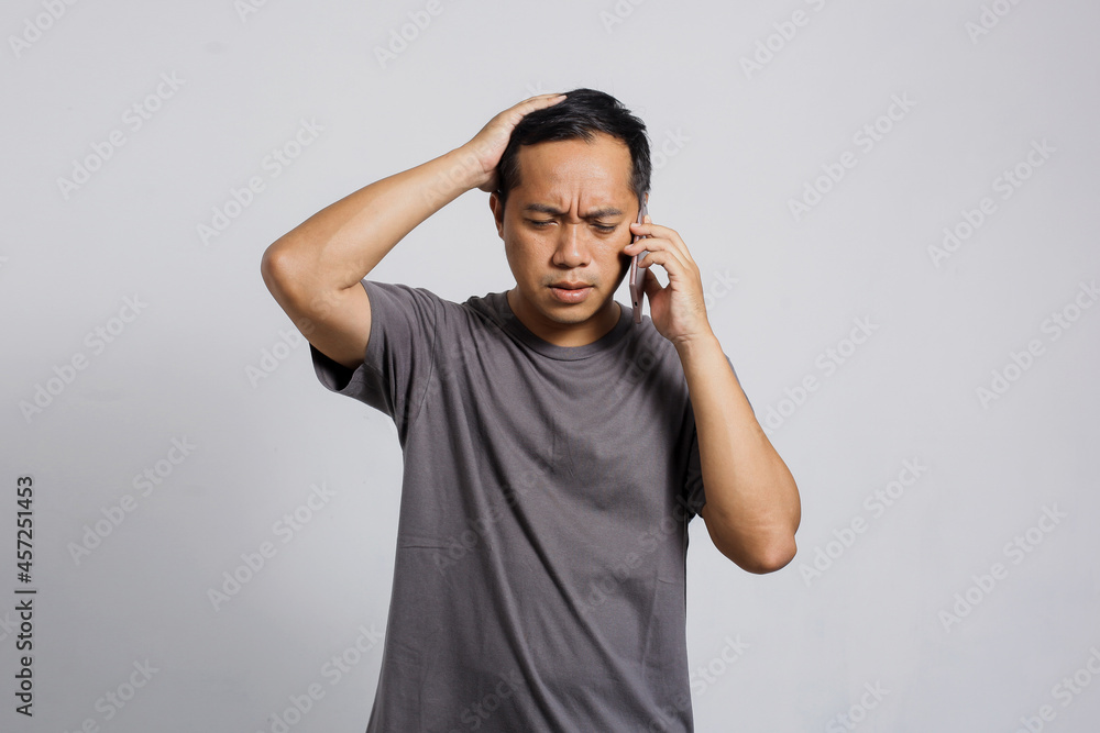 Stressful Asian man doing call by smart phone Stressful Asian man doing call by smart phone