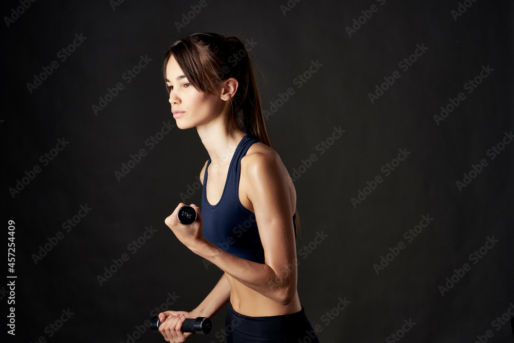 pretty brunette slim figure sport exercise with dumbbells in hands dark background pretty brunette slim figure sport exercise with dumbbells in hands dark background