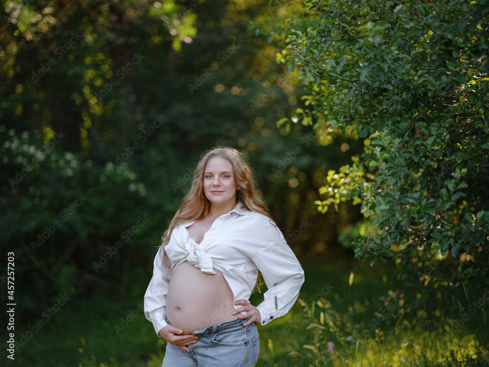 blonde pregnant woman in white shirt and jeans enjoys the silence and beauty of nature. idea of Health and beauty of pregnancy blonde pregnant woman in white shirt and jeans enjoys the silence and beauty of nature. idea of Health and beauty of pregnancy