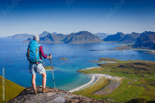 Woman hiker enjoying at the top of the mountain and looking at incredible views of a Norwegian fjord, Lofotens. Travel, adventure, healthy lifestyle concept