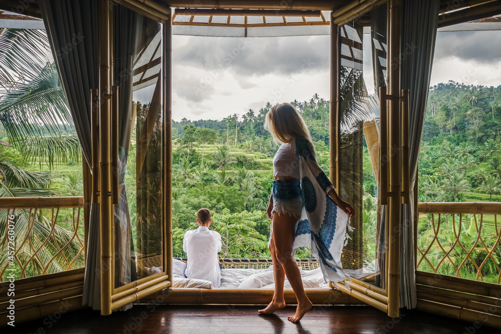 A couple in love sits in a villa in Bali and admires the view of the rice fields.