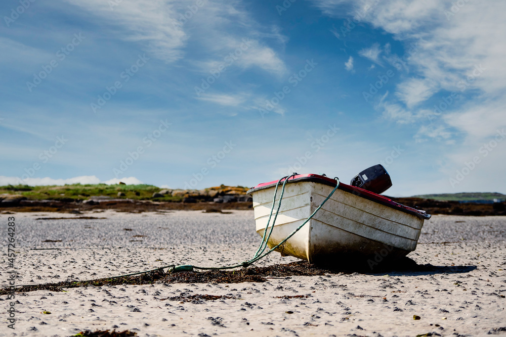 Small white fishing boat on a sand at low tide. Food supply chain industry. Warm sunny day. Small white fishing boat on a sand at low tide. Food supply chain industry. Warm sunny day.