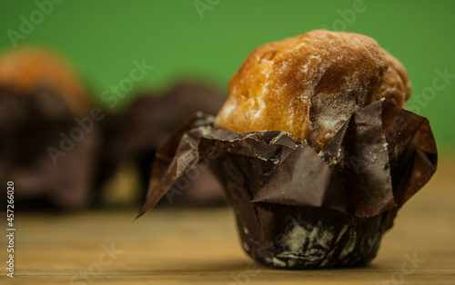 Homemade chocolate and vanilla cupcakes on a wooden table, sprinkled with powdered sugar