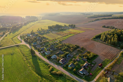 Country houses in the countryside. Aerial view of roofs of green field with rural homes. Village with wooden home. Suburban house at farm. Housing outside the city. Agriculture, farming and agronomy.
