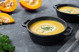 Bowl with pumpkin soup. Vegan creamy soup with coconut milk and butternut squash. Top view. Dark background.