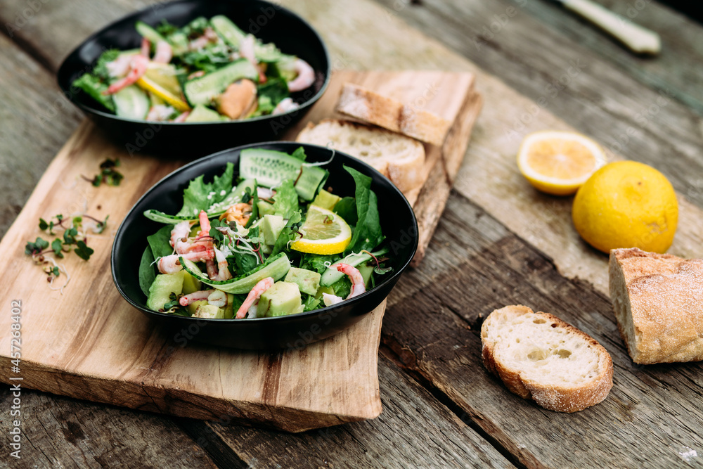 Salad with seafood, vegetables and herbs in a plate on a wooden table. Rustic style