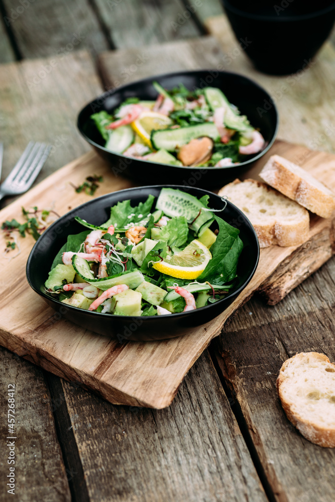 Salad with seafood, vegetables and herbs in a plate on a wooden table. Rustic style Salad with seafood, vegetables and herbs in a plate on a wooden table. Rustic style