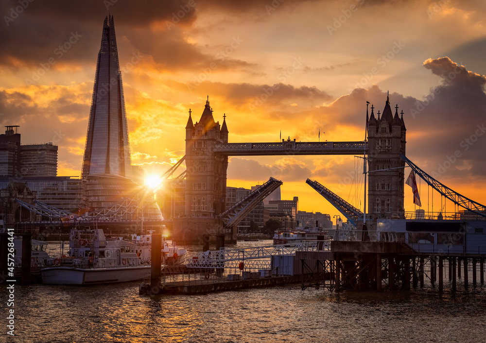 Naklejka premium Beautiful sunset view to the Tower Bridge of London, United Kingdom, lifted up so ships can pass by on the Thames River
