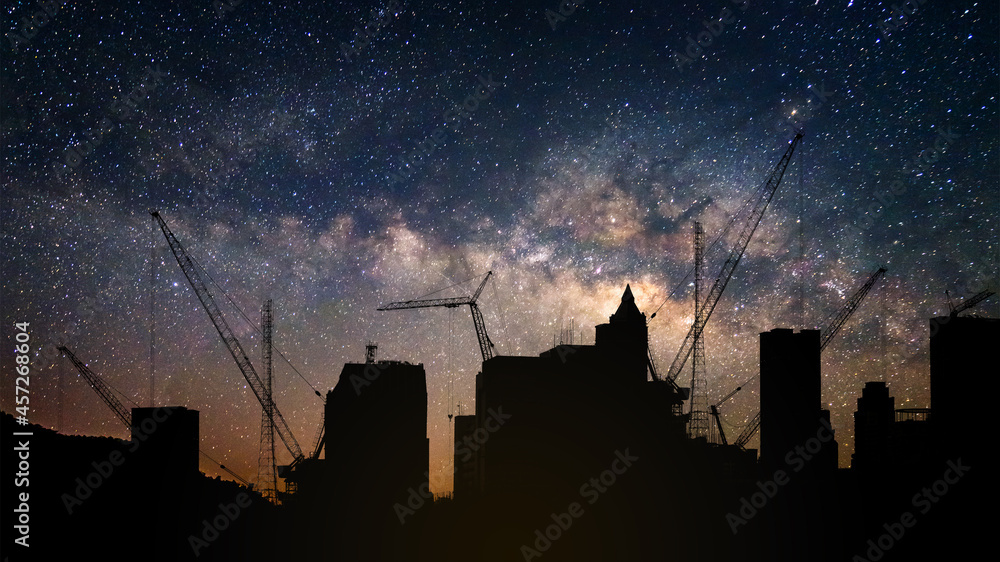 Silhouette of crane tower in the construction site city building with stary night sky and milky way background - obrazy, fototapety, plakaty 