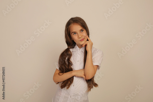 a beautiful teenage girl with long ponytails in a white shirt shows emotions on a white background