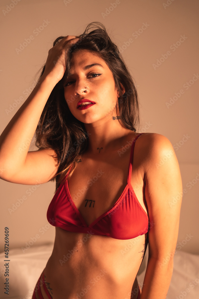 Lifestyle, sexy brunette Caucasian girl with a red tight corset, sensual perched on the bed, illuminated with soft light Lifestyle, sexy brunette Caucasian girl with a red tight corset, sensual perched on the bed, illuminated with soft light