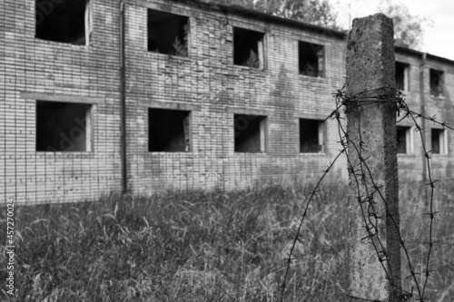 an old barbed wire fence with a abandoned building in the background