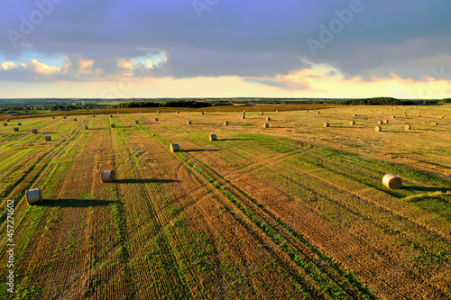 Haystack on field on blue sky background. Hay bale from residues grass. Hay stack for agriculture. Hay in rolls after combine harvester working in wheat field. Harvest season. Haystacks making