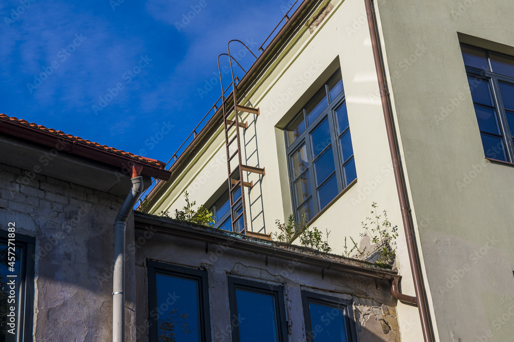 Abstract conceptual architecture of vintage roofs of houses with windows, balconies and oven and ventilation pipes against blue sky with clouds in old Town. Apartments in the attic against skyline