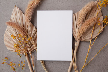 Bohemian blank invitation card surrounded by natural dried palm leaf and grasses. Wedding and celebration background