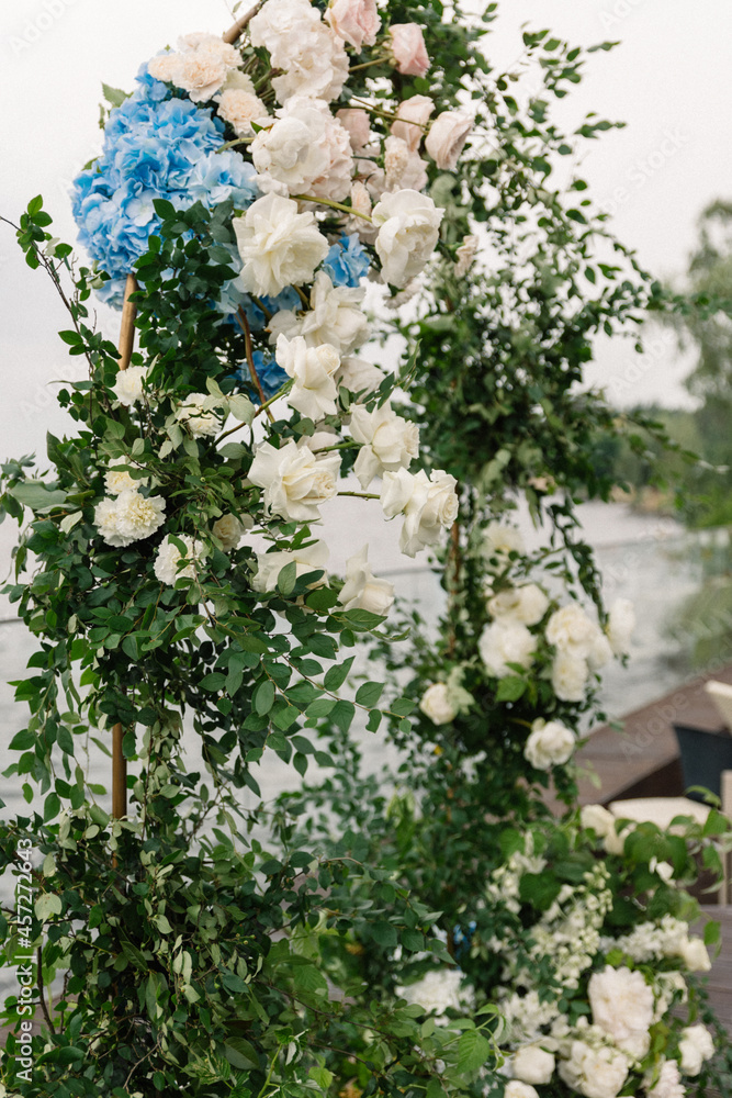 Luxury wedding arch with lush leaves, delicate roses and purple hydrangea outdoors. Wedding floristry Luxury wedding arch with lush leaves, delicate roses and purple hydrangea outdoors. Wedding floristry