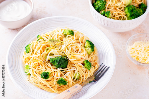 Broccoli and avocado pasta with grated cheese on stone background