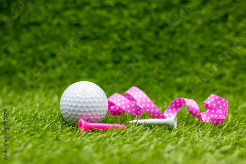 Golf ball with with pink ribbon on green grasss photo