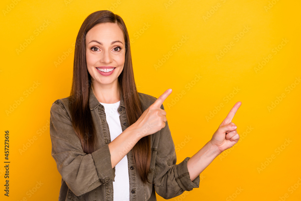 Photo of positive excited young woman point finger empty space news isolated on yellow color background Photo of positive excited young woman point finger empty space news isolated on yellow color background