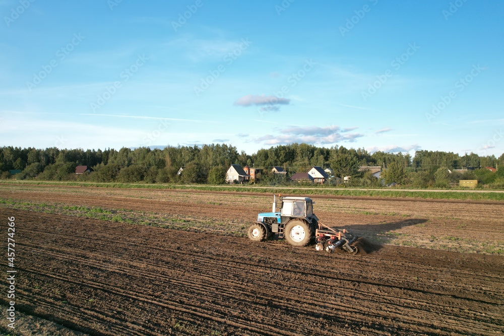 Obraz premium Tractor on cultivating field work. Soil Tillage in farmers country. Agricultural tractor on cultivation field. Sowing seeds. Farming and seeding. Planting Equipment and Farm Machine.