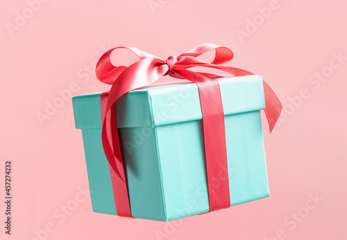 Fototapeta Naklejka Na Ścianę i Meble -  Blue gift box with ribbon on pink background close-up.