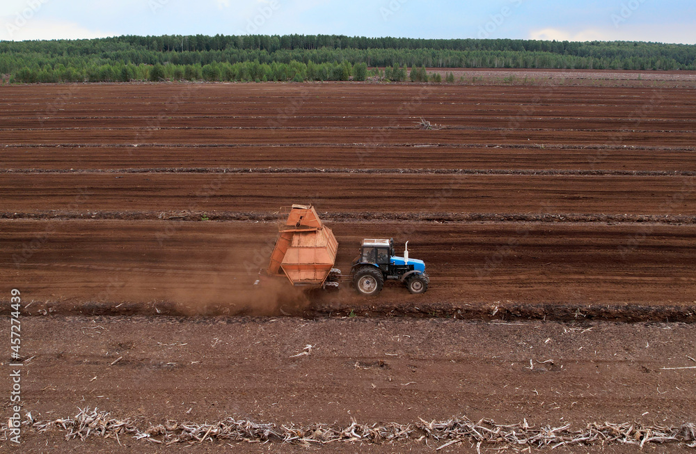 Obraz premium Peat Harvester Tractor on Collecting Extracting Peat. Mining and harvesting peatland. Area drained of the mire are used for peat extraction. Drainage and destruction of peat bogs.