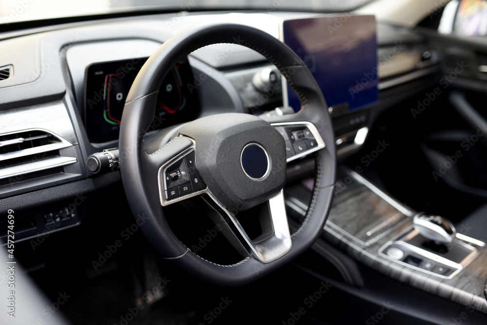 Steering wheel of an electric modern car. Car interior. Driver's seat with steering wheel and electronic display, navigation, climate control and other options. Perforated leather and seat ventilation