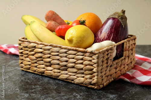 Basket with vegetables and fruits on kitchen towel on black smokey table