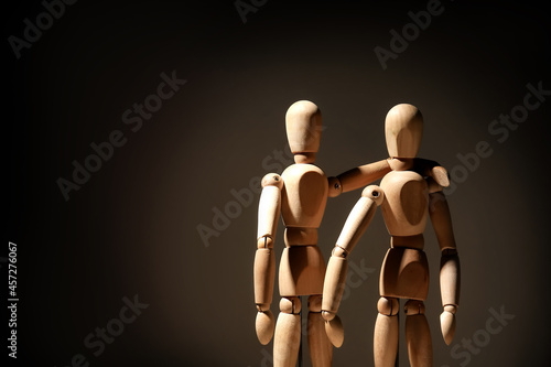 Wooden mannequins on dark background. Concept of friendship