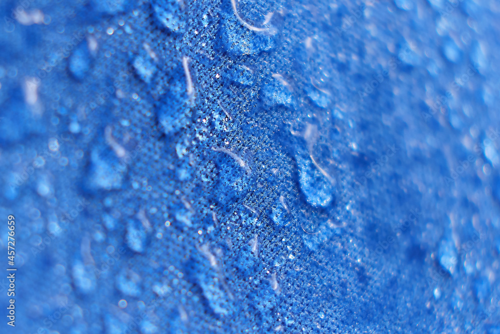 Water drops on the fabric. Rain Water droplets on blue fiber waterproof fabric. Water drops pattern over a waterproof cloth. Blue background.