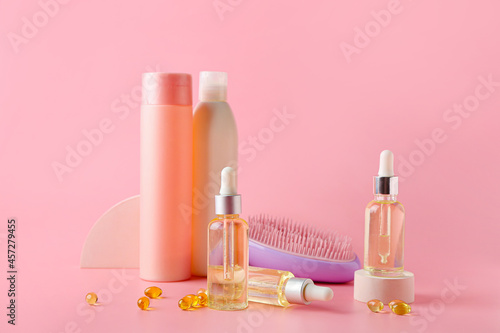 Cosmetic bottles with pills and brush on color background