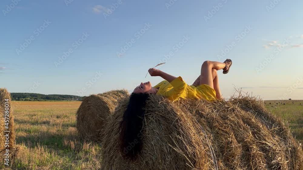 4k Thoughtful young woman in yellow dress relaxing on a straw stack. 4k Thoughtful young woman in yellow dress relaxing on a straw stack.