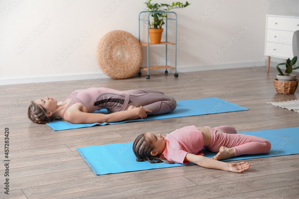 Fototapeta premium Little girl with her mother practicing yoga at home