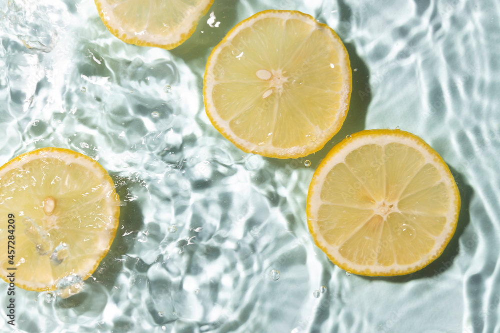 Bright cosmetics background.Top view and closeup of slices of fresh lemon in the water.Vitamin ingredients Bright cosmetics background.Top view and closeup of slices of fresh lemon in the water.Vitamin ingredients