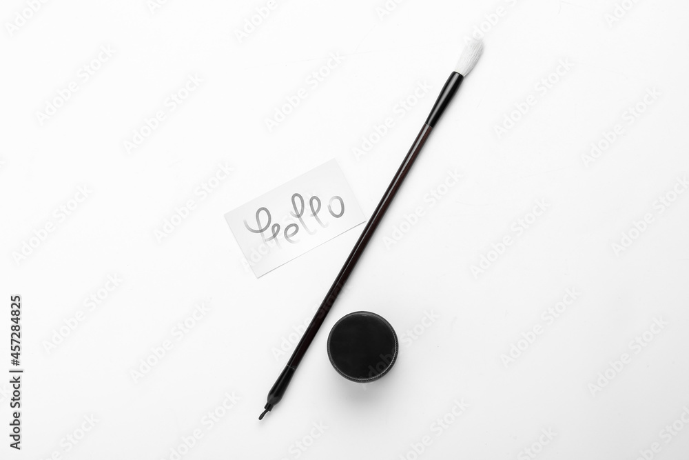 Paper with word HELLO, brush and ink on white background Paper with word HELLO, brush and ink on white background